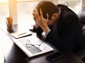 tired business man with head on his hands looking down on computer